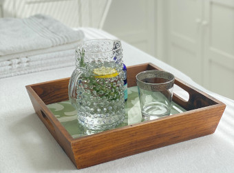 Part of a white massage table with white towels and pitcher and glass of fresh water with lemon.